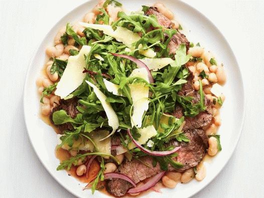 Fotografie cu o friptură flancată cu rozmarin și salată de rucăi