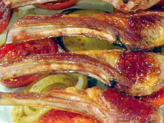 Fotografie a unui raft de miel pe o pernă de roșii și ceapă picante