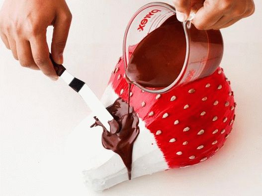 Topiți ciocolata cu unt, întindeți fundul tortului, lăsând ciocolata să se scurgă de căpșuni.